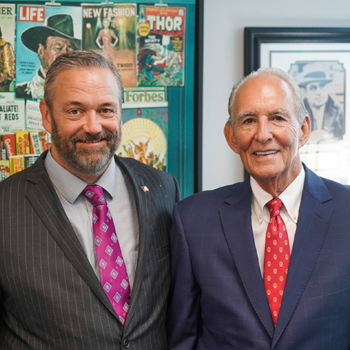 Two men in suits posing for a picture.